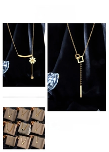 Detail of gold pendant necklaces featuring heart, square, and floral charms on black silk