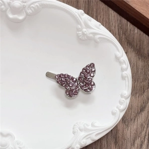 Detailed view of a purple rhinestone butterfly hair clip on a vintage ceramic tray