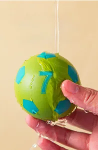 Macro view of a 6cm bouncy ball being rinsed under water to show its waterproof surface