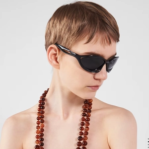 Side view of a female model wearing Y2K cat-eye sunglasses with a beaded necklace accessory