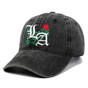Detailed close-up of gothic LA letter embroidery and red rose on washed black baseball cap
