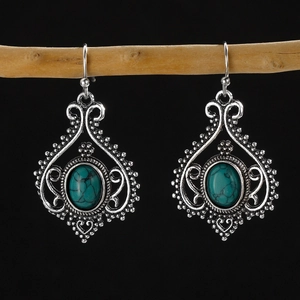 Detailed view of silver bohemian earrings with turquoise stones on a wooden branch