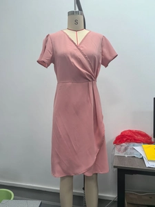 Détail d'une robe portefeuille rose avec col en V et plis latéraux élégants sur mannequin