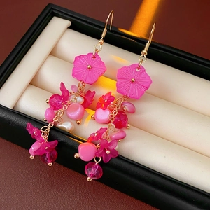 Boucles d'oreilles fleurs roses avec glands de perles et crochets dorés sur un coffret