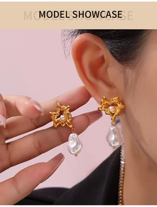 Detail of vintage gold starburst earrings featuring oversized white baroque pearl pendants