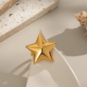 Makroaufnahme eines klobigen goldenen Sternrings auf geometrischem Stein-Display