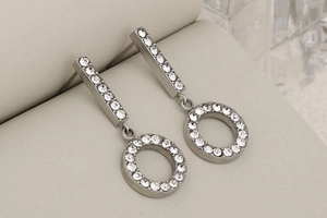 Close-up of silver earrings with hollow circular drops and sparkling pavé crystal inlay