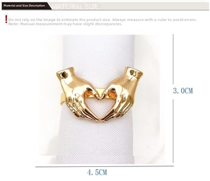 Detailed view of heart-shaped gesture napkin ring in gold finish on white cloth