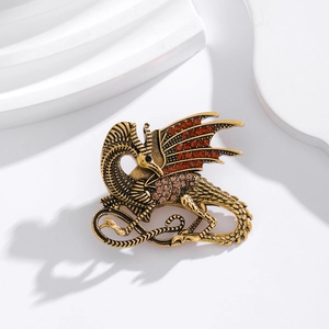 Detailed close-up of a vintage bronze dragon brooch with inlaid red and clear gemstones
