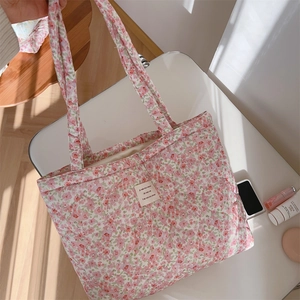Macro shot of floral quilted cotton tote bag detail with beige fabric label and shadow