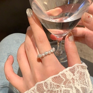 Gros plan sur bague en perles et pavé de diamants portée avec dentelle