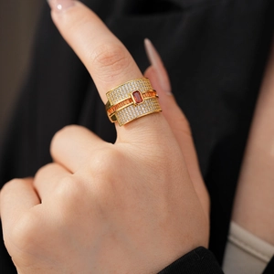Close-up of gold-plated ring with orange rectangular gemstone and pavé zircon on finger