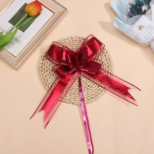 Detail view of a large red metallic gift bow with sheer edges on a woven mat