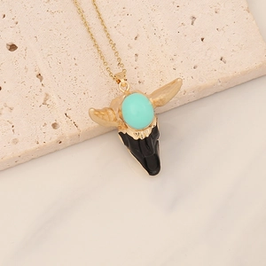 Detail view of a bull head pendant with turquoise stone on beige stone texture