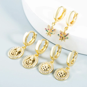 Detail of gold earrings set featuring crystal maple leaf, pineapple, and ladybug charms