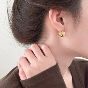 Close-up of chunky gold hoop earrings with polished finish on model's ear
