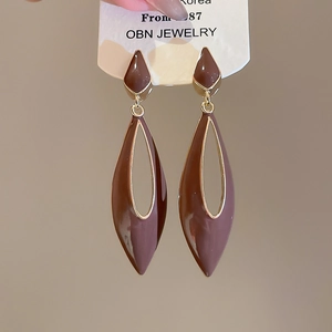 Detailed view of hollow drop earrings with dark brown enamel and gold finish