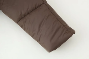 Close-up of matte brown winter jacket cuff showing stitching detail and windproof fabric