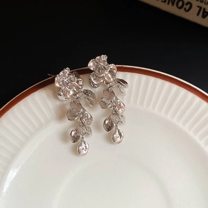 Detail of silver floral tassel earrings showing intricate metallic petals and long drops
