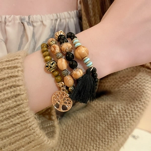 Detail of bohemian multilayer sandalwood beaded bracelet with tree of life charm and tassel