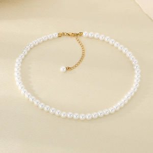 Dettaglio della collana di perle con chiusura dorata su sfondo minimalista strutturato