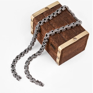 Detailed silver dragon scale necklace with dragon head clasp on vintage wooden box