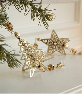 Close-up of golden metal Christmas tree ornament with amber beads hanging on pine branch