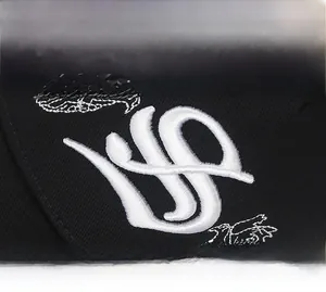 Close-up of white embroidered dove and musical note on black cotton baseball cap