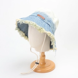 Close-up of denim bucket hat featuring frayed edges and a brown leather logo patch