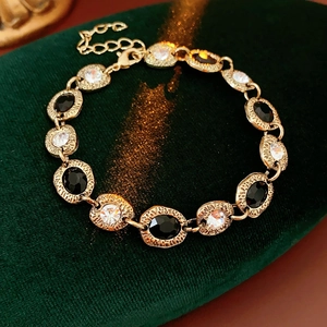 Détail d'un bracelet vintage doré avec gemmes noires et blanches sur velours