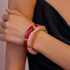 Détail de bracelets en perles acryliques rouges et roses avec accents cylindriques dorés