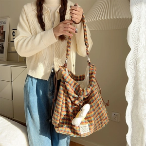 Detail of plaid wool shoulder bag with drawstring closure and soft cloud charm
