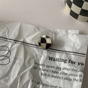 Detailed view of a round black and white checkered hair clip with a smooth glazed surface