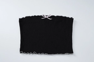 Détail d'un haut bustier noir smocké avec petit nœud rose et bordures volantées