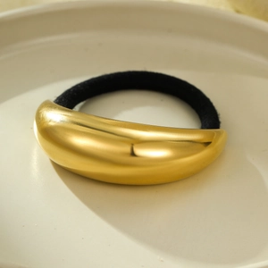 Close-up of golden curved metal starfish hair tie on a beige ceramic plate