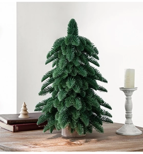 Close-up of a 55cm mini PE artificial Christmas tree with a natural wooden base on a table