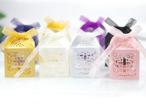 Close-up of laser-cut hollow cross candy boxes with ribbon bows in various colors