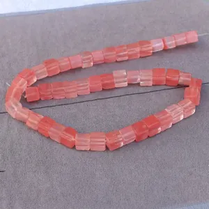Macro detail of square pink natural stone beads on gray velvet for DIY jewelry making