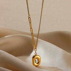 Macro shot of 18K gold plated oval pendant with zircon on champagne silk fabric