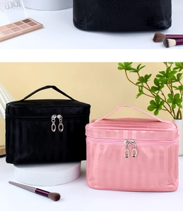 Detail of pink and black cosmetic bags with striped texture and dual silver zippers