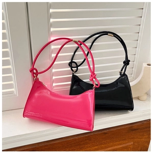 Close-up of glossy patent leather baguette bags with knotted straps in pink and black