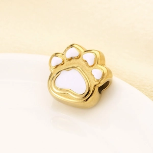 Macro view of gold paw bead with white heart enamel detail for DIY jewelry making
