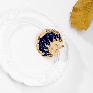 Macro detail of sun goddess brooch with blue enamel moon and gold face texture