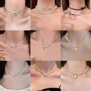 Collage de neuf colliers en perles blanches avec nœuds et pendentifs fleuris pour femme