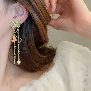 Elegant gold butterfly tassel earrings with green beads and pearl drop on model