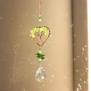 Detail of tree of life heart suncatcher showing green peridot stones and crystal pendant
