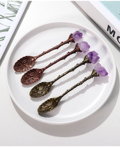 Macro view of vintage bronze spoons with raw amethyst crystals and floral engravings