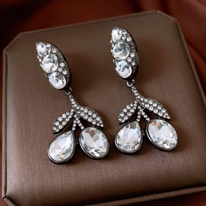 Détail de boucles d'oreilles vintage avec cristaux blancs sur métal noir fusil