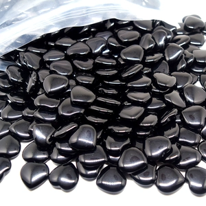 Close-up of small black heart-shaped natural stones spilling out from a clear bag