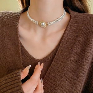 Close-up of double-layer pearl necklace with a rhinestone-encrusted oval pendant